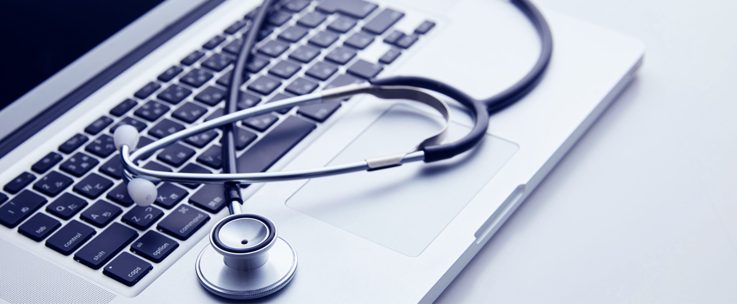 Laptop with a stethoscope lying on keyboard